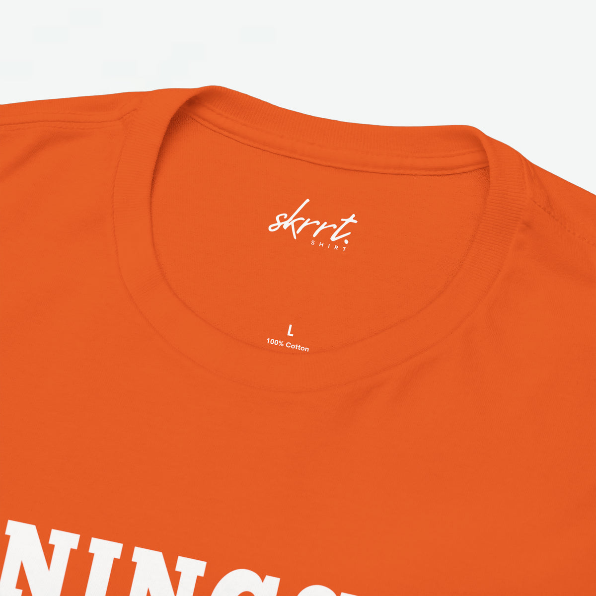 Oranje T-shirt halsboord met klein 'skrrt' logo en '100% katoen' label