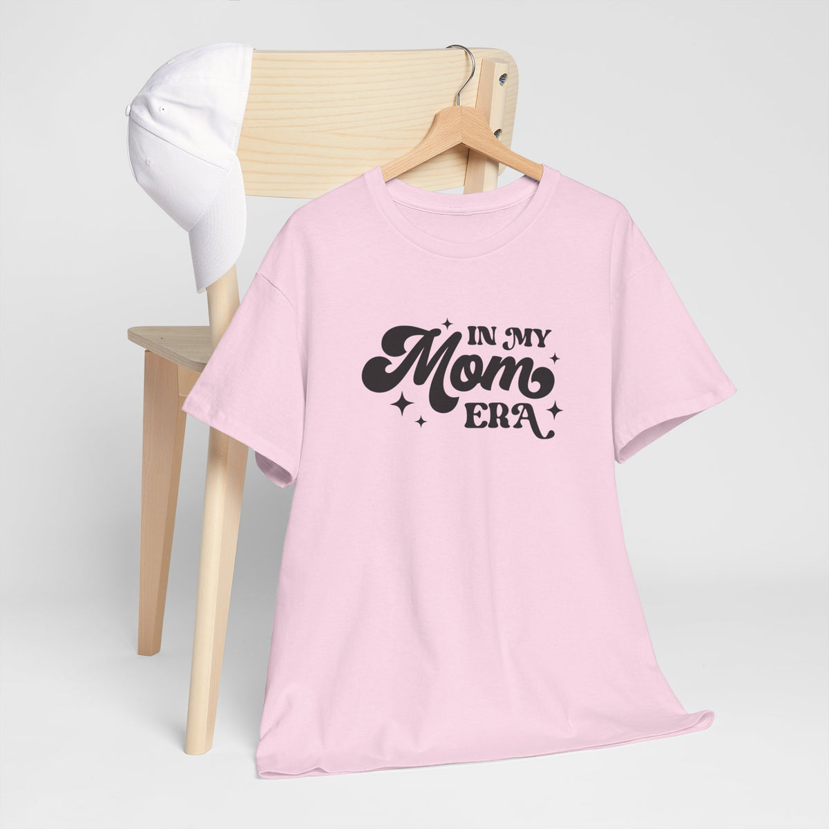 Roze T-shirt met borstprint “In my Mom Era” op een houten hangertje.