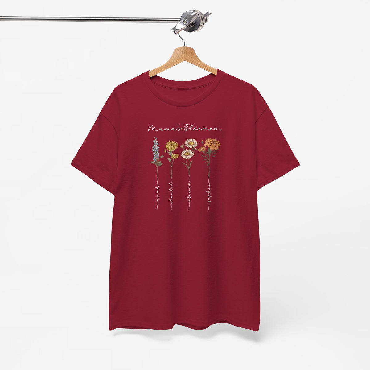 Rood T-shirt op houten hanger met witte opdruk “Mama’s Bloemen” en bloemenprint.