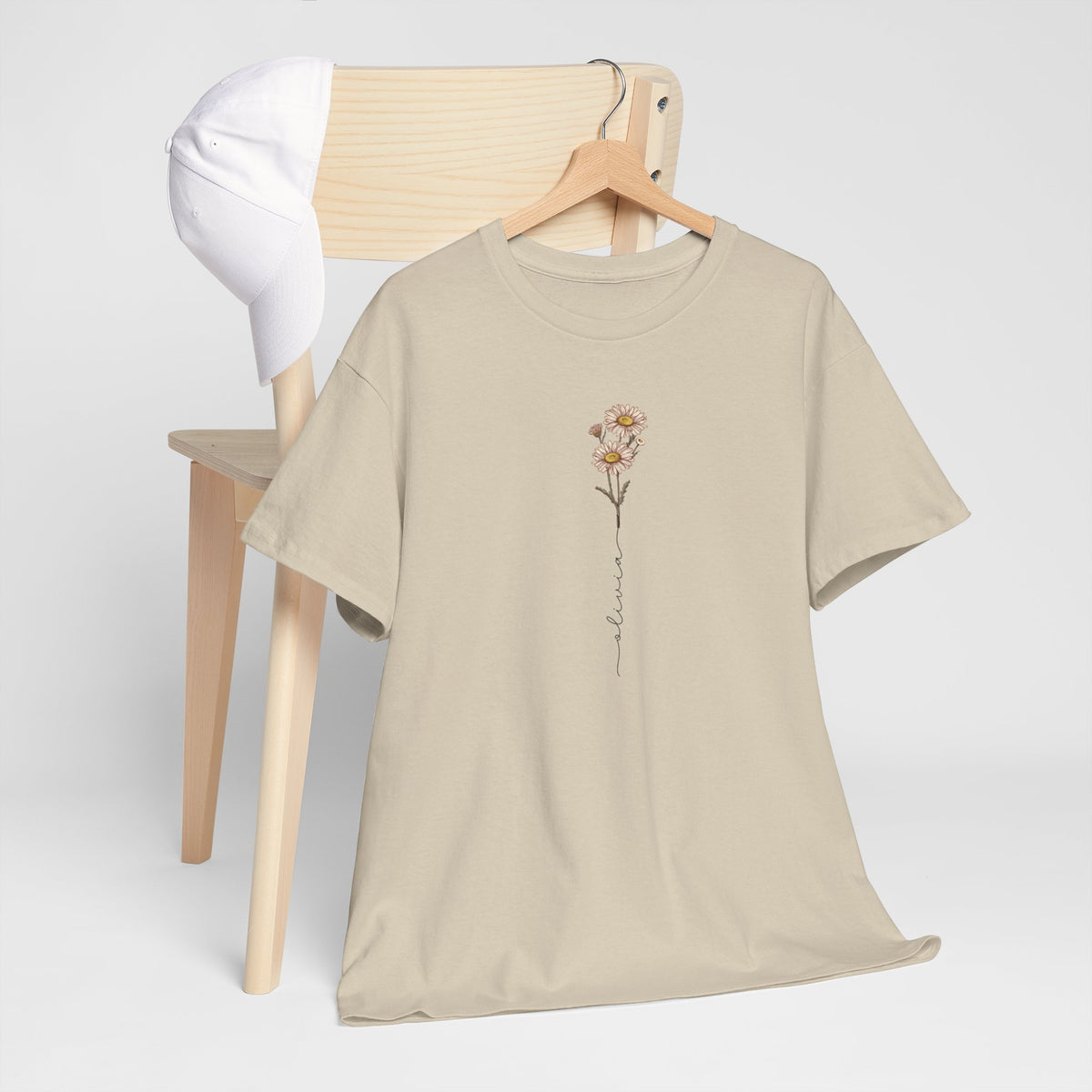 Zandkleurig T-shirt met bloemillustratie op de borst, opgehangen aan houten hanger