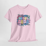 Roze T-shirt met bloemenprint en kleurrijke tekst “BONUS MAMA” op de borst.