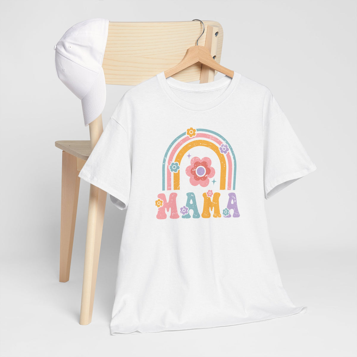 Witte T-shirt met regenboogprint en 'MAMA' op de borst, opgehangen op stoel