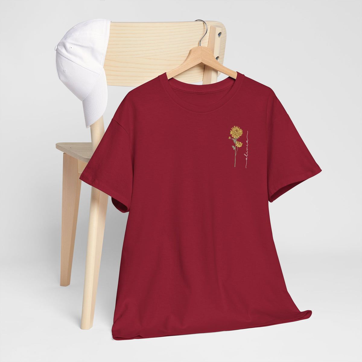 Rode T-shirt met ronde hals en kleine goudkleurige bloemillustratie op de borst.
