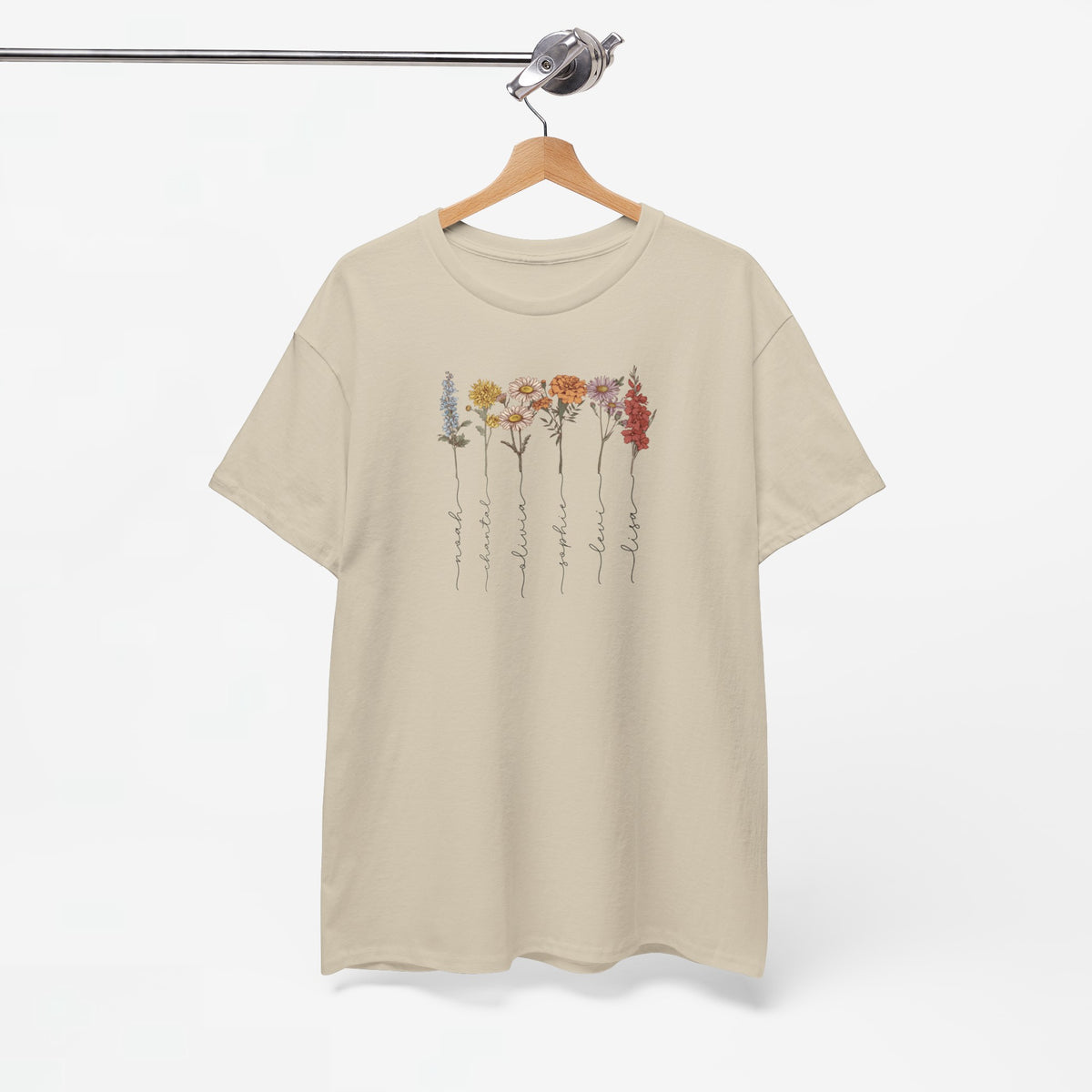 Beige T-shirt met bloemenillustratie en sierlijke namen, opgehangen.