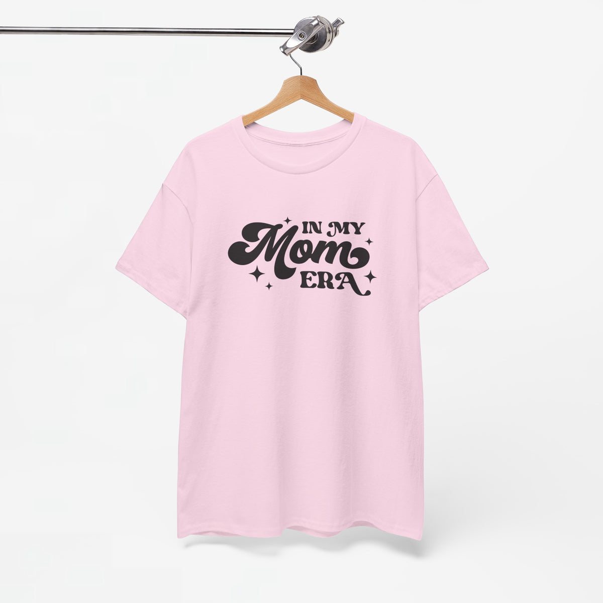 Roze T-shirt aan een houten hanger met borstprint “In my Mom Era”.
