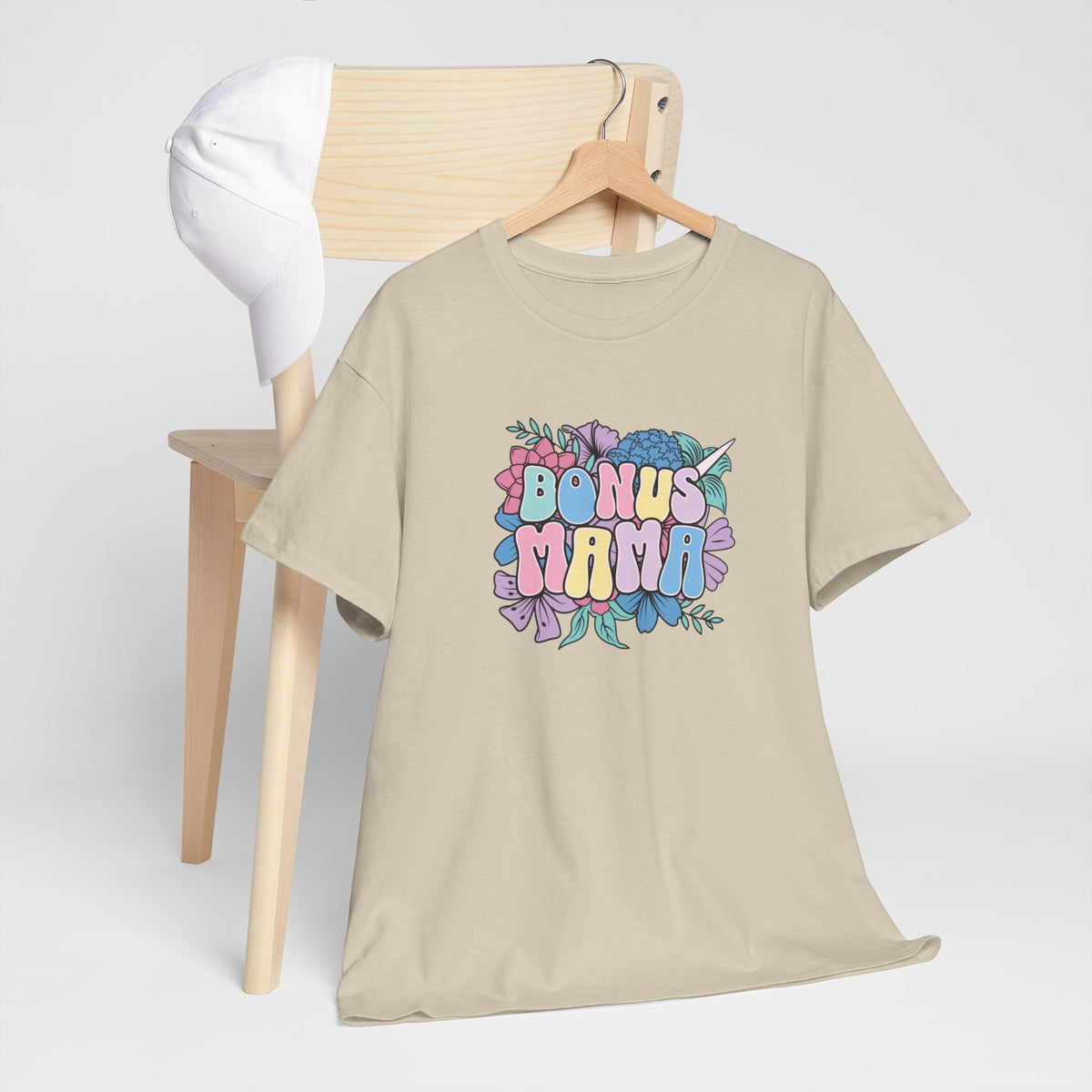 Beige oversized t-shirt met ‘BONUS MAMMA’ bloemenprint, liggend op stoel