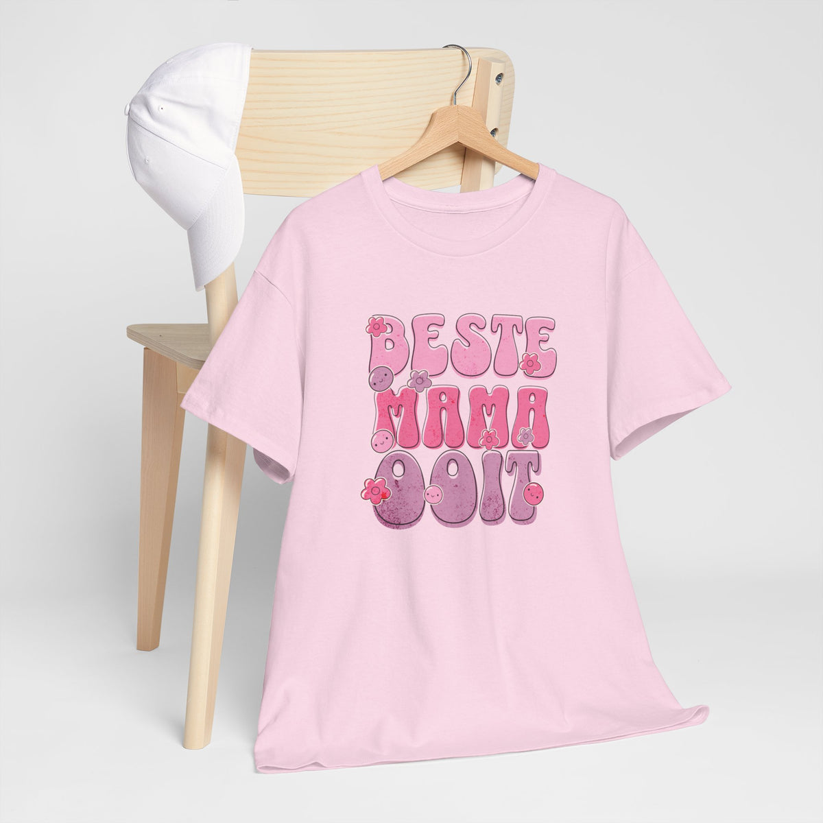 Roze T-shirt met 'Beste Mama Ooit' opdruk in roze en paars, opgehangen aan houten hanger.