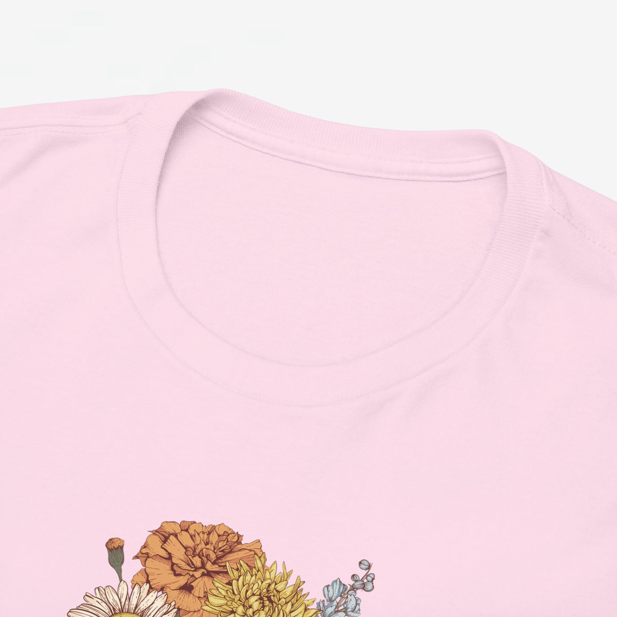 Roze T-shirt close-up: ronde hals en bloemboeketprint onderaan beeld.