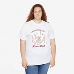 Witte t-shirt met handenillustratie en rode tekst Moms Club, gedragen met blauwe jeans.
