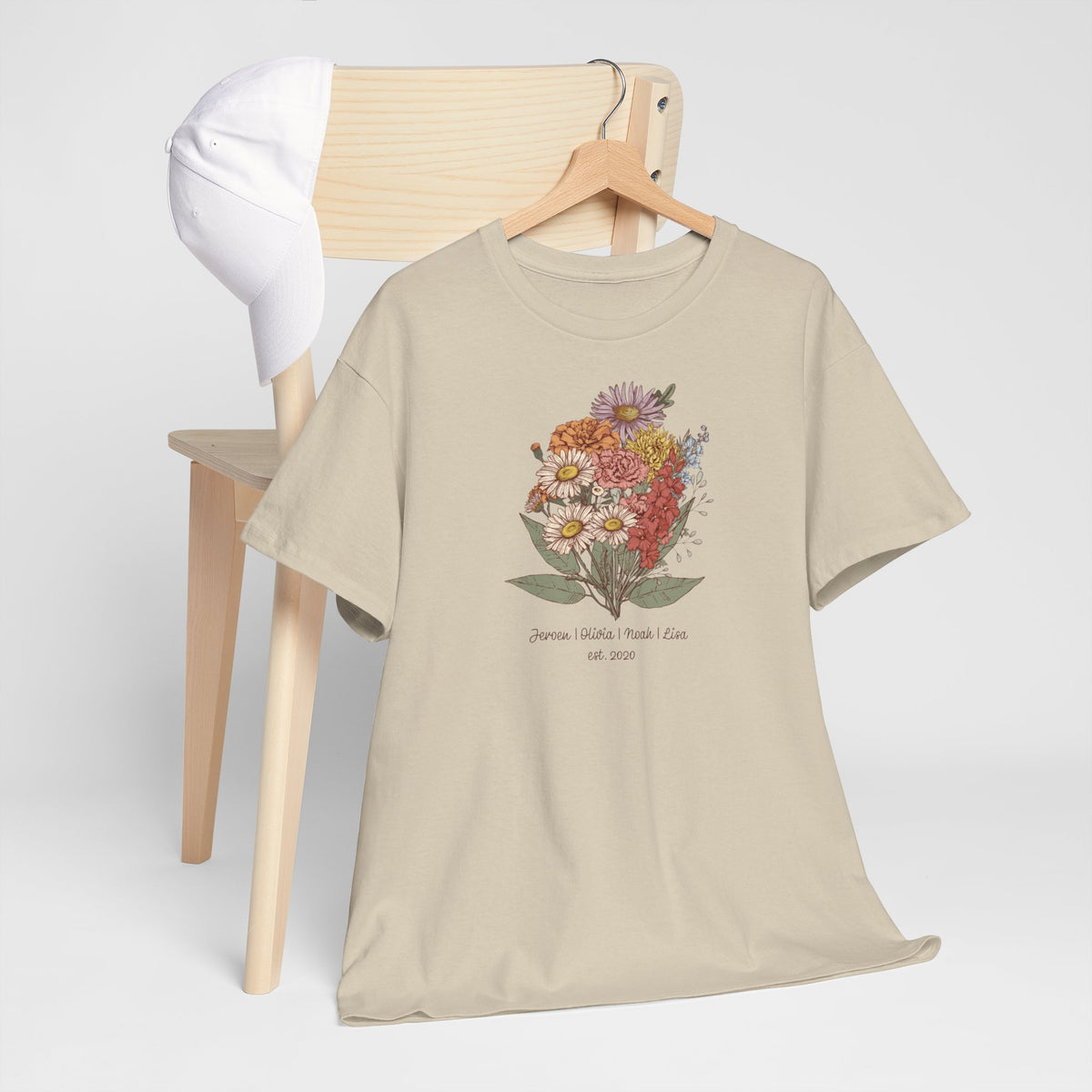 Beige t-shirt met bloemenprint op de borst, te zien op een houten stoel