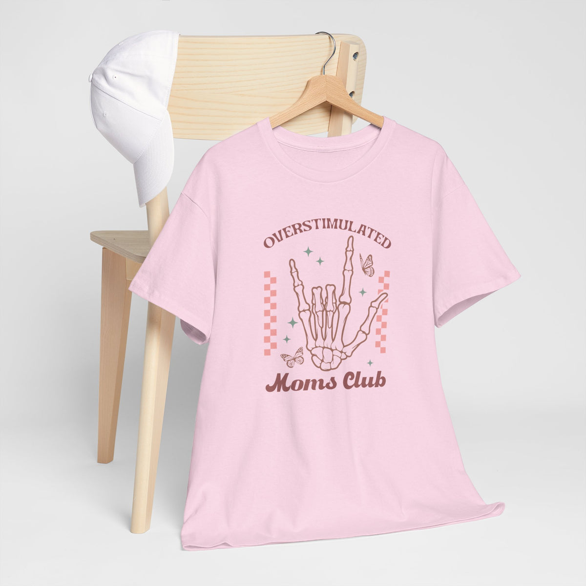 Roze T-shirt met handillustratie en tekst op de borst, naast hangende item.