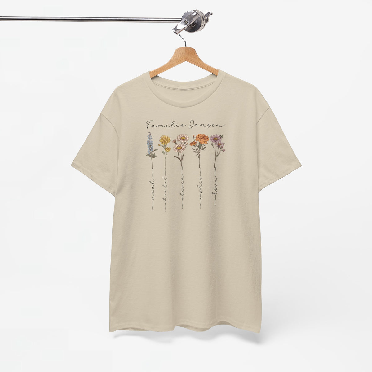 Zandkleurige t-shirt aan kleerhanger met bloemenprint en familienaam voorop