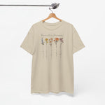 Zandkleurige t-shirt aan kleerhanger met bloemenprint en familienaam voorop