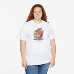Wit T-shirt met bloemenboeket-print op de borst; model draagt het met blauwe jeans