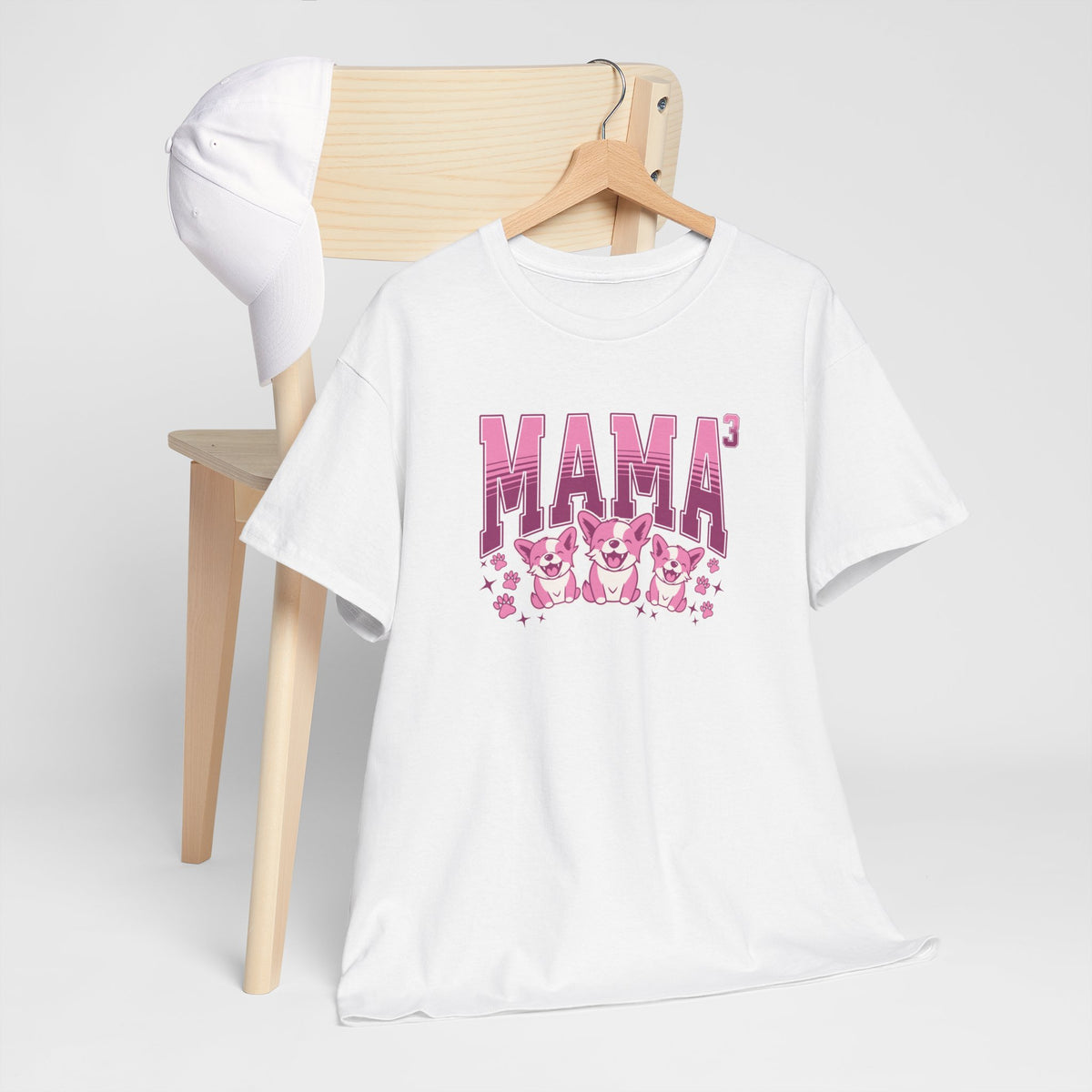 Witte T-shirt met roze 'MAMA3' print en kattenfiguren, opgevouwen om een stoel