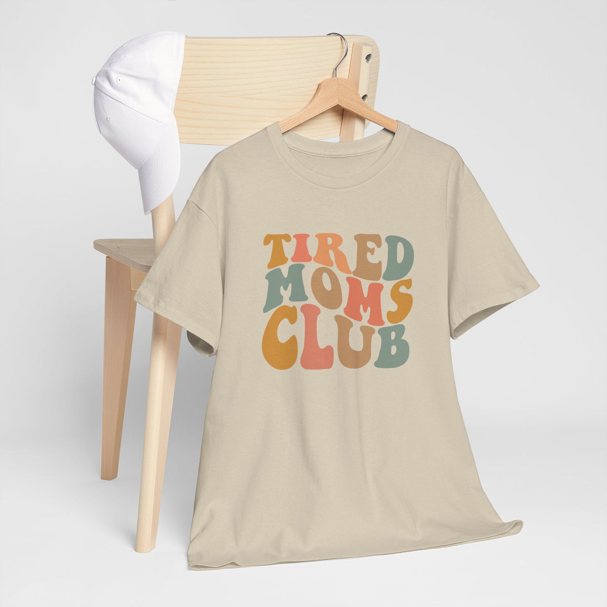 Beige T-shirt met ronde hals en opdruk “Tired Moms Club”, op hangertje.