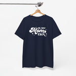 Donkerblauwe t-shirt met ronde hals en witte tekst “In My Mom ERA”, aan een houten hanger.