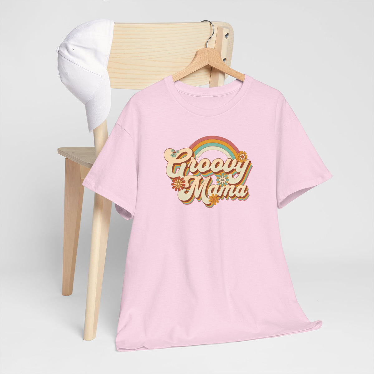 Roze T-shirt met ronde hals en “Groovy Mama” print, naast een houten stoel