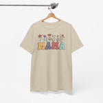 Beige T-shirt met kleurrijke 'Mama' opdruk en bloemen, hangt aan houten hanger.