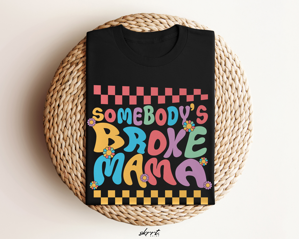 Zwart t-shirt met kleurrijke "Somebody’s Broke Mama"-opdruk, opgevouwen in mandje