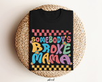 Zwart t-shirt met kleurrijke "Somebody’s Broke Mama"-opdruk, opgevouwen in mandje