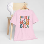 Roze T-shirt aan hanger, ronde hals en multikleurenprint “IN MY PLANT MOM ERA”.