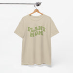 Beige T-shirt aan hanger met ronde hals en groene “PLANT MOM”-opdruk.