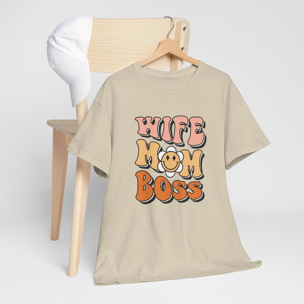 Zandkleurig los T-shirt met ronde hals en bedrukking “WIFE MOM BOSS”, opgehangen.