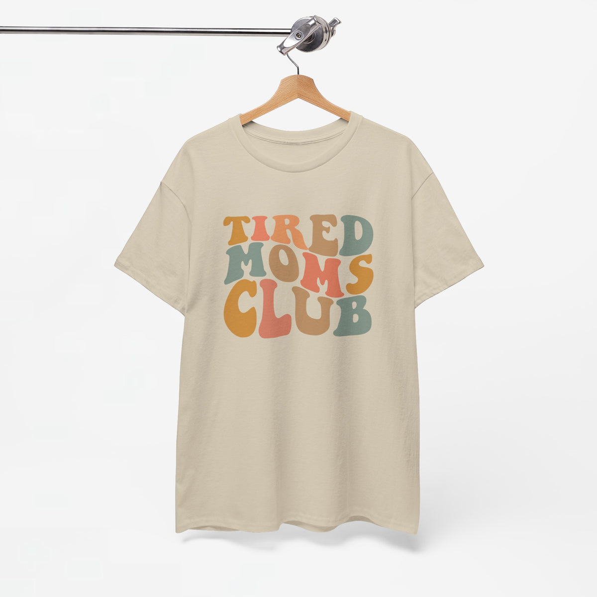 Beige T-shirt met ronde hals en opdruk “Tired Moms Club”, opgehangen.