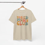 Beige T-shirt met ronde hals en opdruk “Tired Moms Club”, opgehangen.