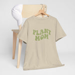 Beige T-shirt aan hanger met groene “PLANT MOM” tekst, korte mouwen.