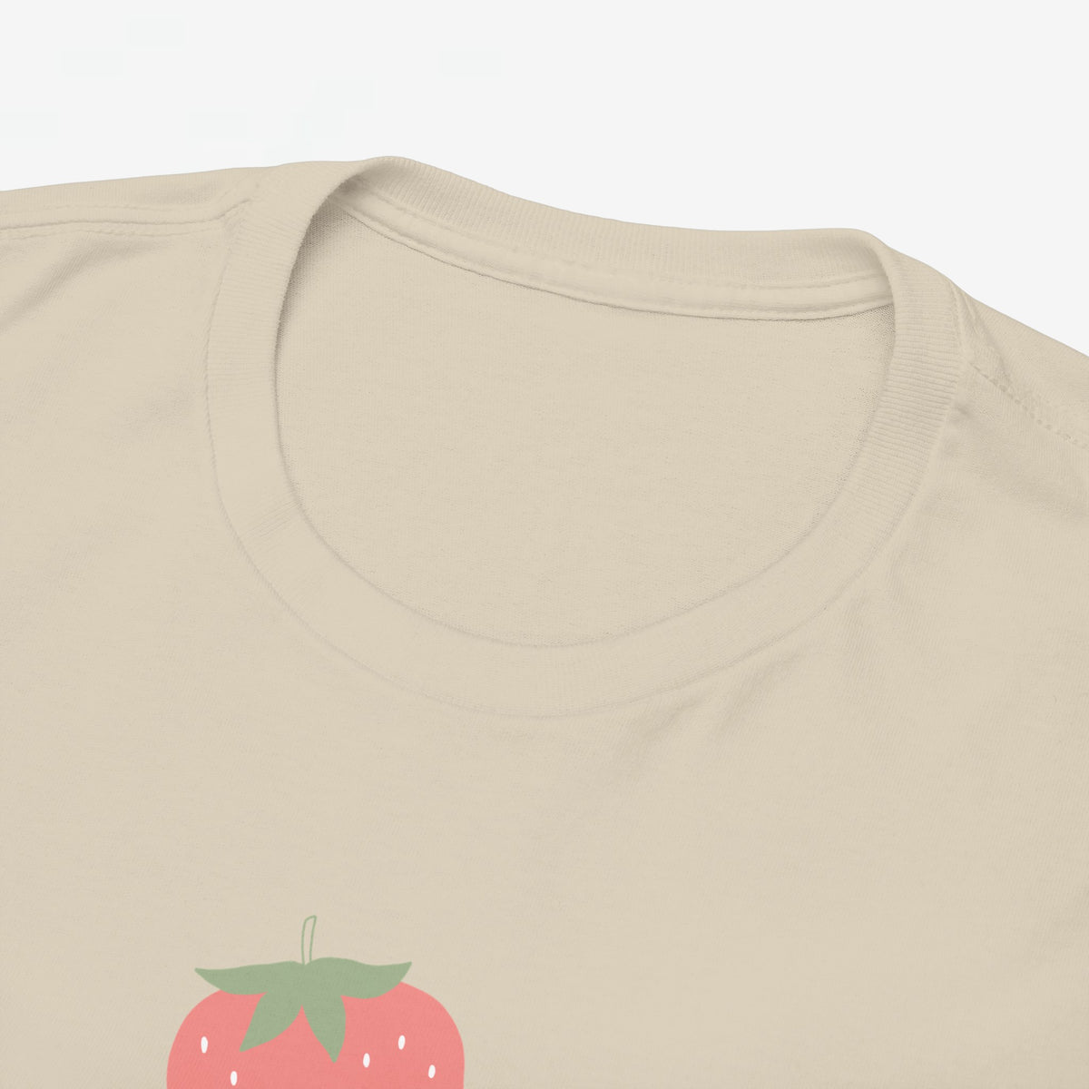 Oversized zandkleurige T-shirt halsboord en klein deel van aardbeienprint.