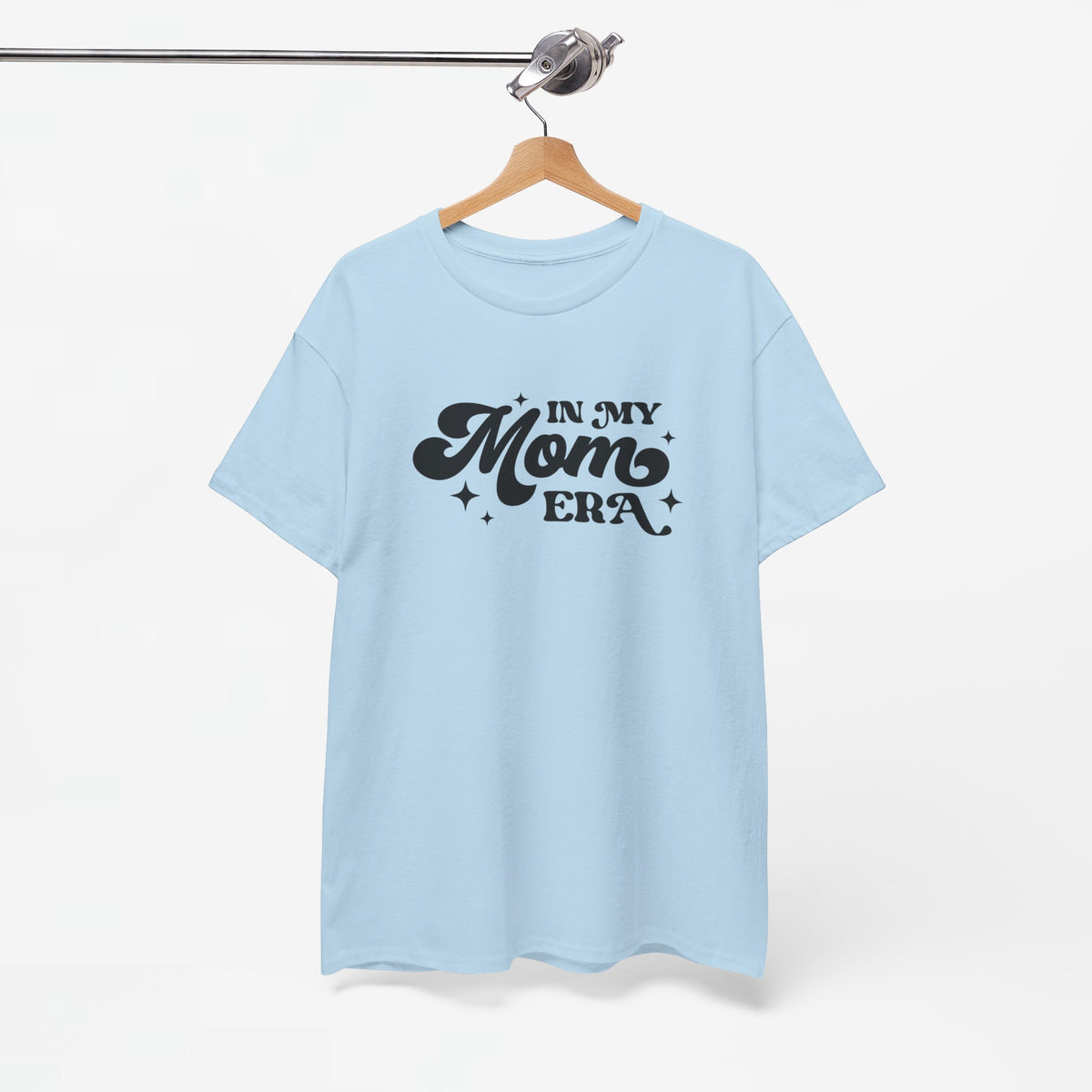 Lichtblauwe t-shirt aan een houten hanger met zwarte "In My Mom Era"-print.
