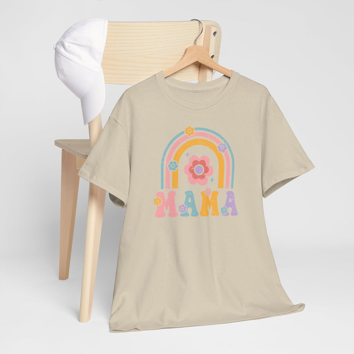 Zandkleurig T-shirt met regenboog- en bloemprint en tekst MAMA vooraan, op houten hanger.