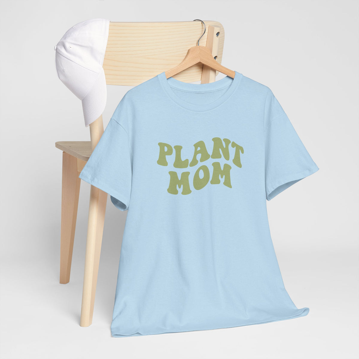 Lichtblauwe T-shirt met groene 'PLANT MOM'-print op houten hanger, met witte T-shirt erbij