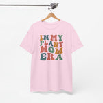 Roze T-shirt aan een hanger, met ronde hals en multikleurenprint “IN MY PLANT MOM ERA”.