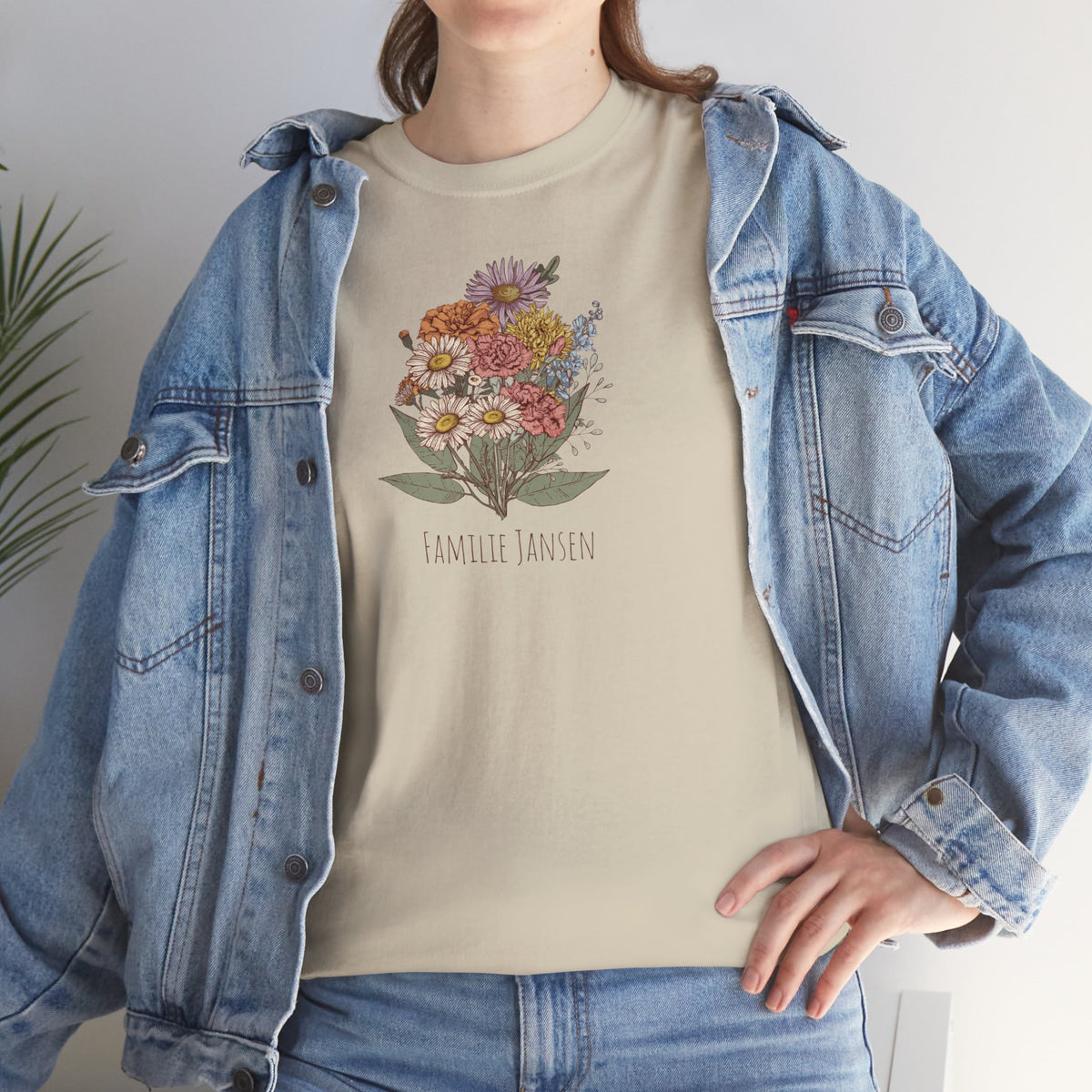 Beigekleurig T-shirt met bloemenprint en tekst op de borst, onder denim jas