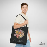 Zwarte tote bag met bloemenboeketprint en naam Elizabeth, gedragen aan de schouder.