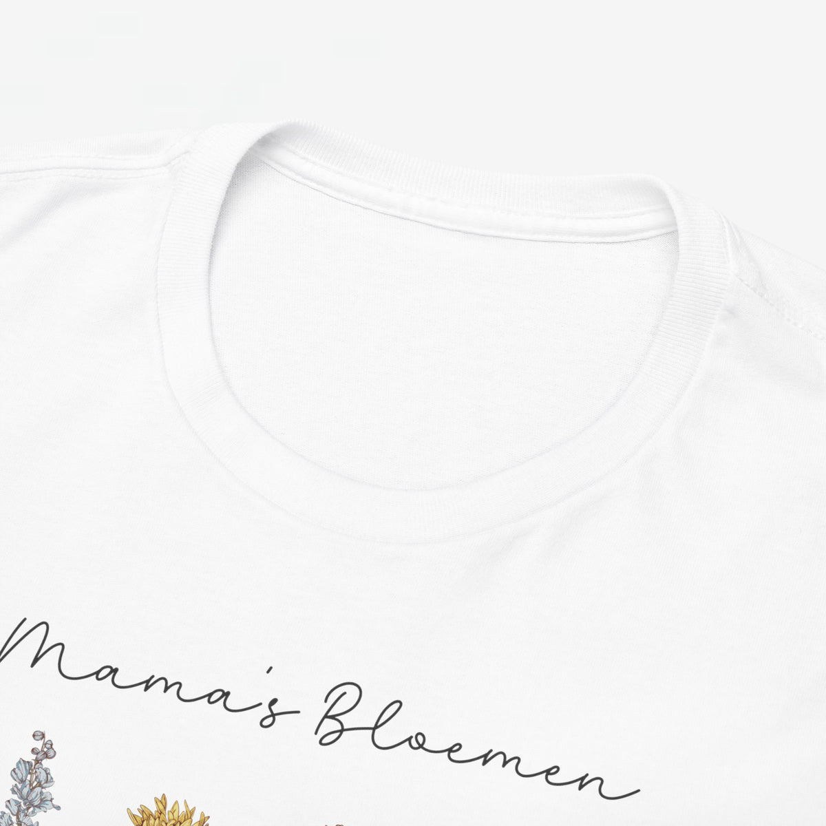 Close-up: witte T-shirt hals met subtiele opdruk “Mama's Bloemen”.