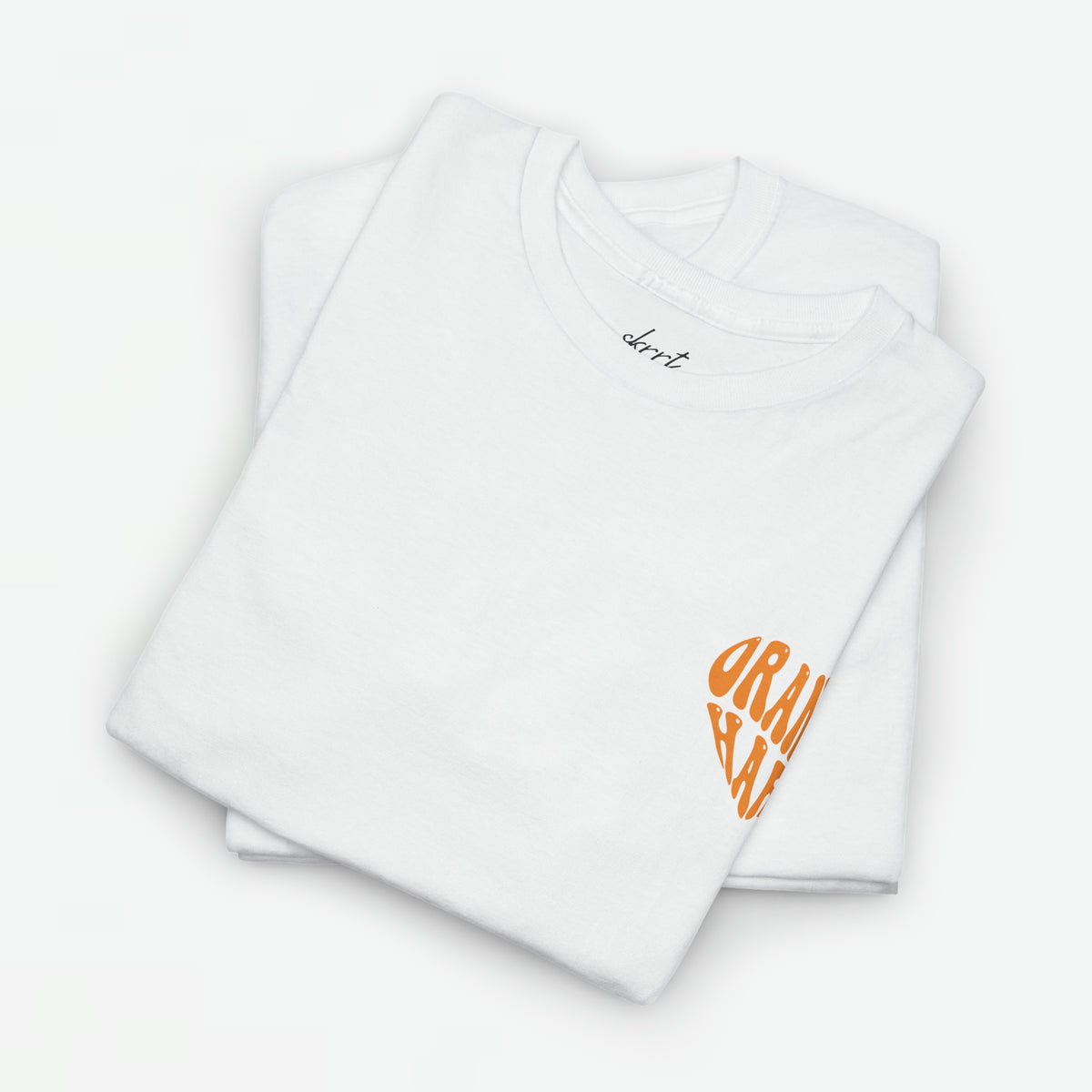 Oversized Koningsdag T-shirt voor dames, witte stof met klein oranje borstlogo, opgevouwen set.