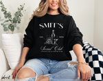 Zwarte sweatshirt op model met “SMIT’S Social Club” print en fles/glas
