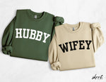 Koppel sweatshirts: olijfgroen HUBBY en zandkleurig WIFEY, ronde hals.
