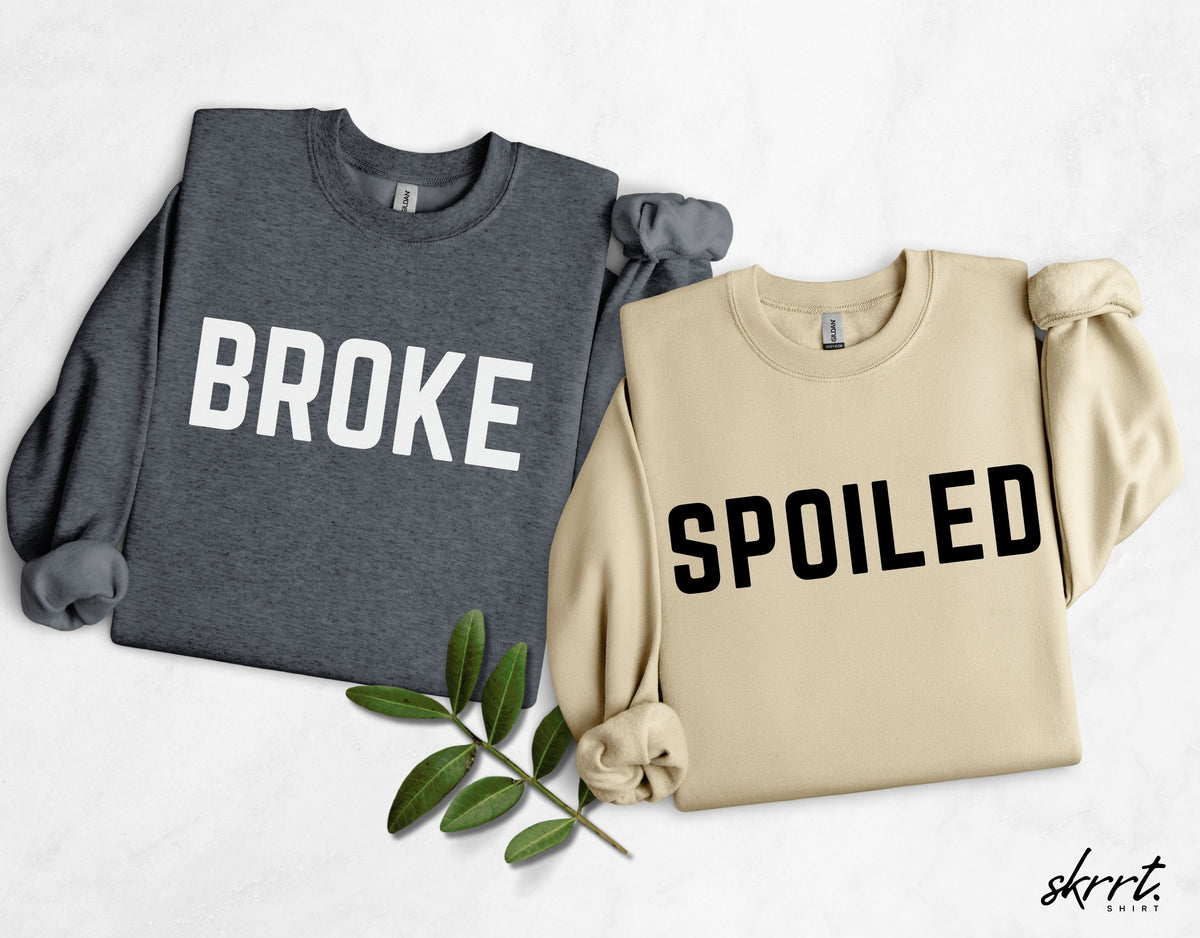 Set van twee sweatshirts: grijs met BROKE en beige met SPOILED, met decoratieve bladeren.