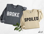 Set van twee sweatshirts: grijs met BROKE en beige met SPOILED, met decoratieve bladeren.