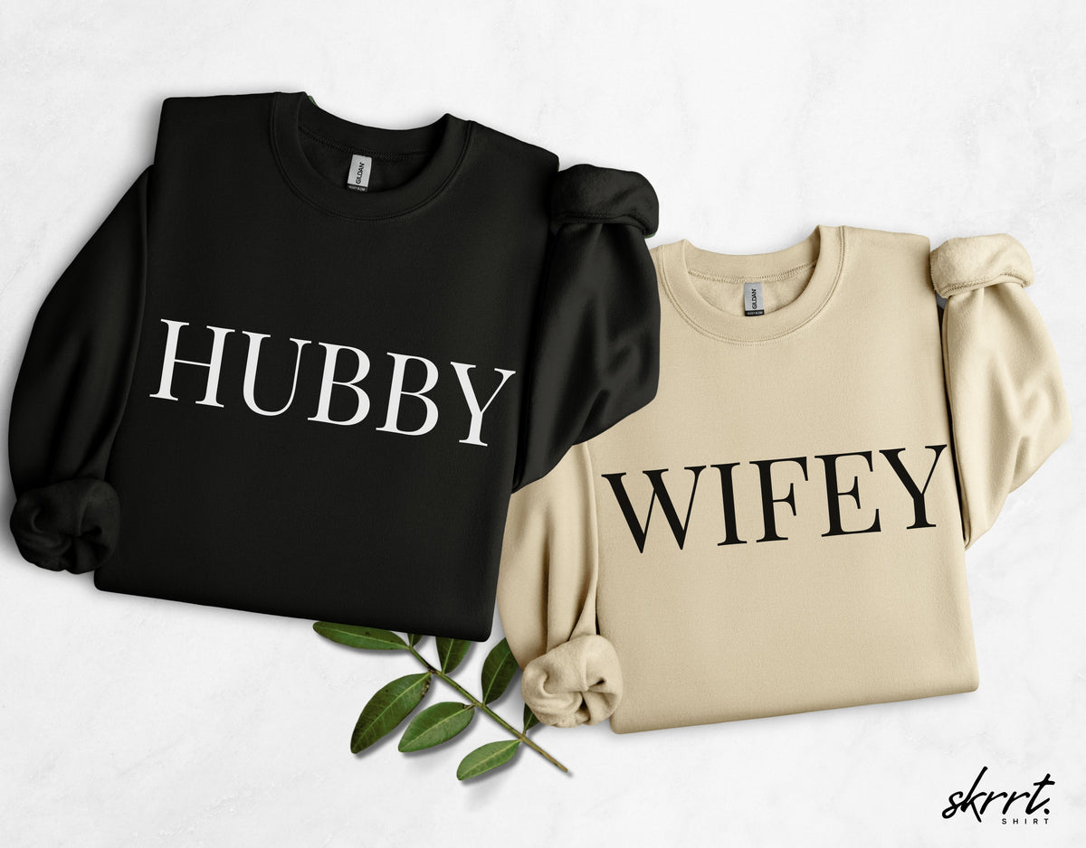 Koppeltruienset: zwarte 'HUBBY' en beige 'WIFEY' sweater.