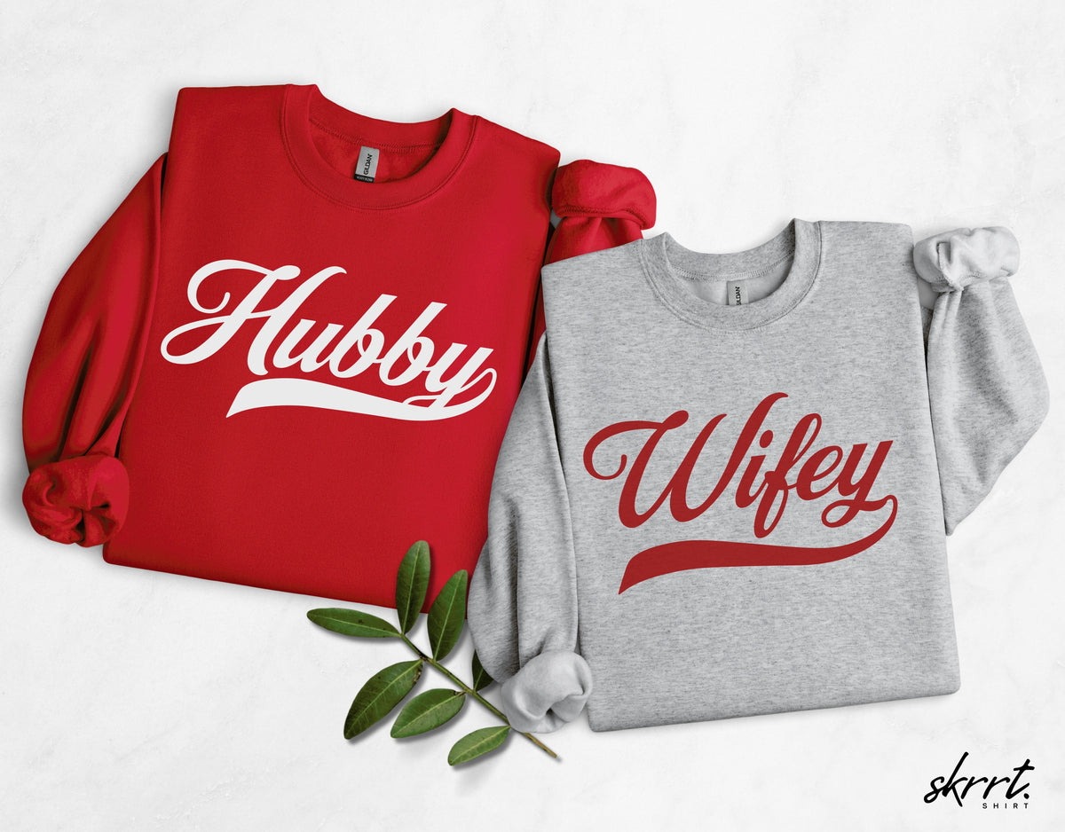 Set van twee sweatshirts: rood 'Hubby' en grijs 'Wifey', met blaadjes op de foto.